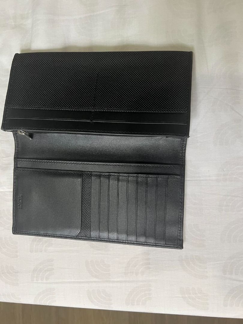 TUMI Black Long Wallet (Category: Wallets & Card holders) located in Manila. Submitted by pengsalvador (Listing ID 1470831706, Image 3). Description: - Brand: TUMI - Material: Durable ballistic nylon with premium leather trim - Color: Classic Black - Exterior: Front flap with iconic metal TUMI logo plate - Interior: Multiple card slots, spacious bill compartments, and a secure zippered pocket - Condition: Clean interior lining and well-maintained