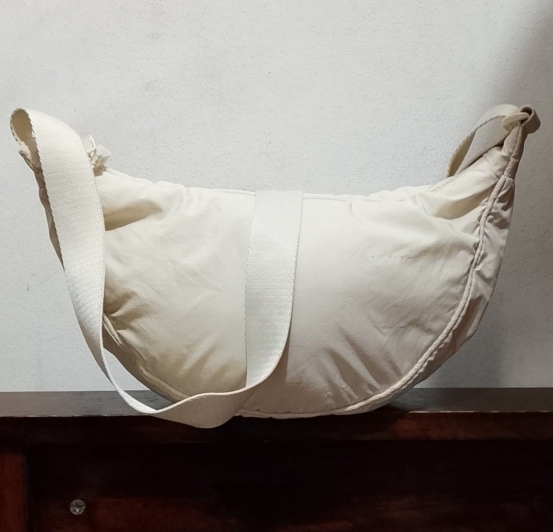 UNIQLO Cross bodybag (Category: Cross-body Bags) located in Tarlac. Submitted by faithfulfinds (Listing ID 1470841914, Image 1). Description: Crescent / Half Moon Nylon Shoulder Bag UNIQLO Condition: Lightly used Details: Has minimal, unnoticeable signs of use but still in good condition. Note: There are some small lints/runs (please check photos for a closer look, but they don't affect the overall use and look of the bag). Color: Off-white Style