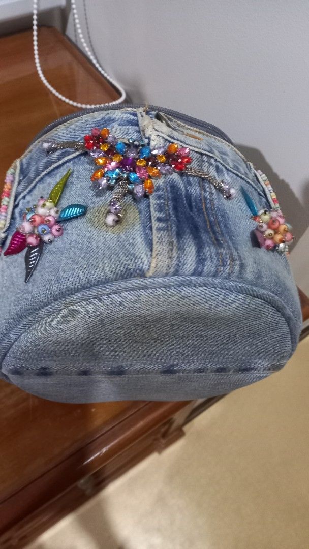 Upcycled Denim Handbag with Beaded Gem Embellishments (Category: Tote Bags) located in Manila. Submitted by miss66449 (Listing ID 1470837964, Image 2). Description: -Girly Style: Upcycled round denim handbag in a light blue wash - Accents: Colorful rhinestone butterflies and beaded flower - Details: Denim top handle, zip closure, black fabric lining, and one inner zip pocket - Origin: Made in Thailand label inside Rarely you can spot selling in m