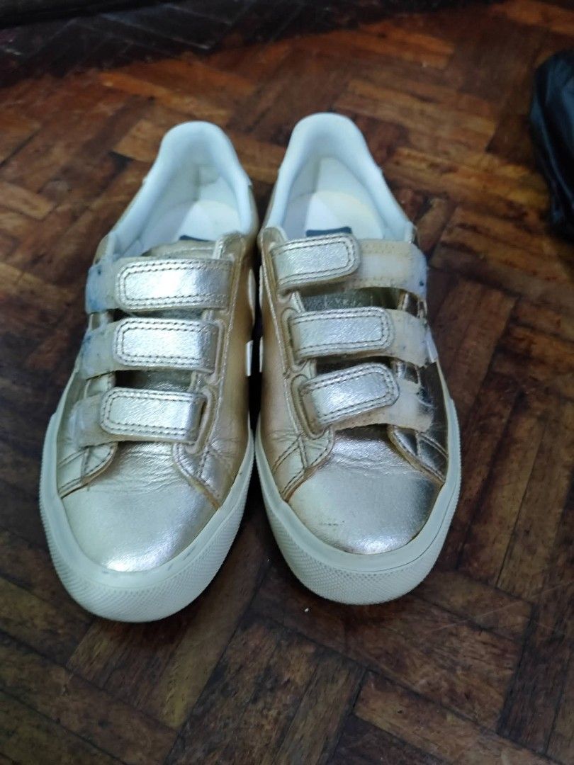 Veja Metallic Gold Velcro Sneakers (Category: Sneakers) located in Bacoor. Submitted by stargazer1084 (Listing ID 1470835822, Image 1). Description: - Brand: Veja - Material: Metallic gold leather with white rubber sole - Style: Triple velcro strap closure with bold VEJA logo branding - Condition: Noticeable wear and dirt buildup on velcro straps; minor scuffs on soles from previous use - Perfect for adding a shiny pop to your everyday casual fit