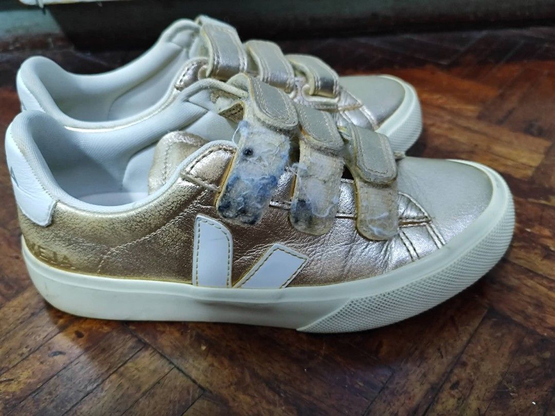 Veja Metallic Gold Velcro Sneakers (Category: Sneakers) located in Bacoor. Submitted by stargazer1084 (Listing ID 1470835822, Image 2). Description: - Brand: Veja - Material: Metallic gold leather with white rubber sole - Style: Triple velcro strap closure with bold VEJA logo branding - Condition: Noticeable wear and dirt buildup on velcro straps; minor scuffs on soles from previous use - Perfect for adding a shiny pop to your everyday casual fit