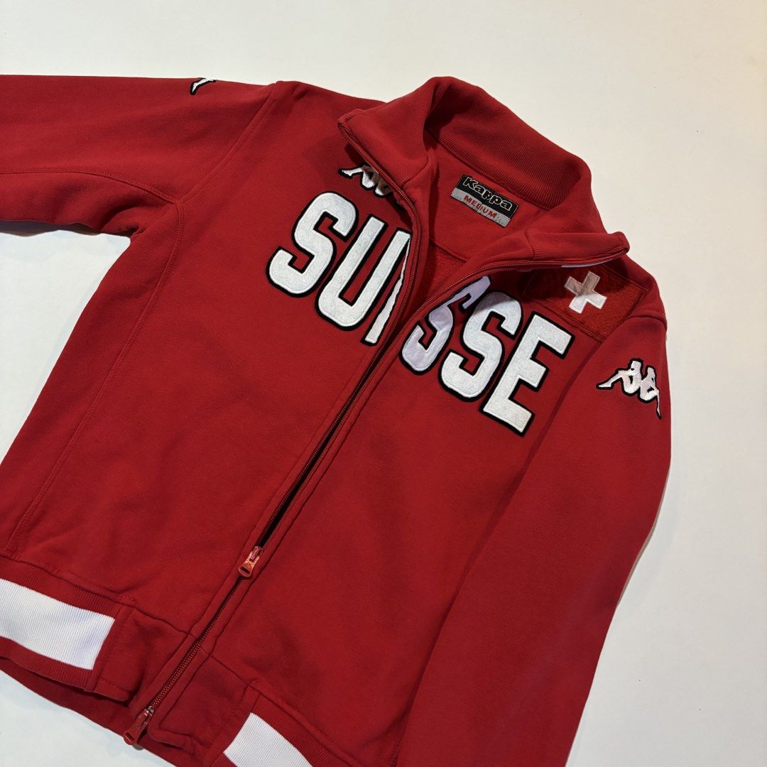 Vintage Kappa Suisse Red Track Jacket Medium (Category: Coats, Jackets and Outerwear) located in Dipolog. Submitted by dionato (Listing ID 1470777617, Image 3). Description: - Brand: Kappa - Style: Red track jacket with white ribbed collar, cuffs, and hem - Design: Large embroidered 'SUISSE' across the chest with classic Kappa logo and stitched Swiss flag patch - Hardware: Full zip front with dual pullers - Size: Medium - Material: Heavy cotton b