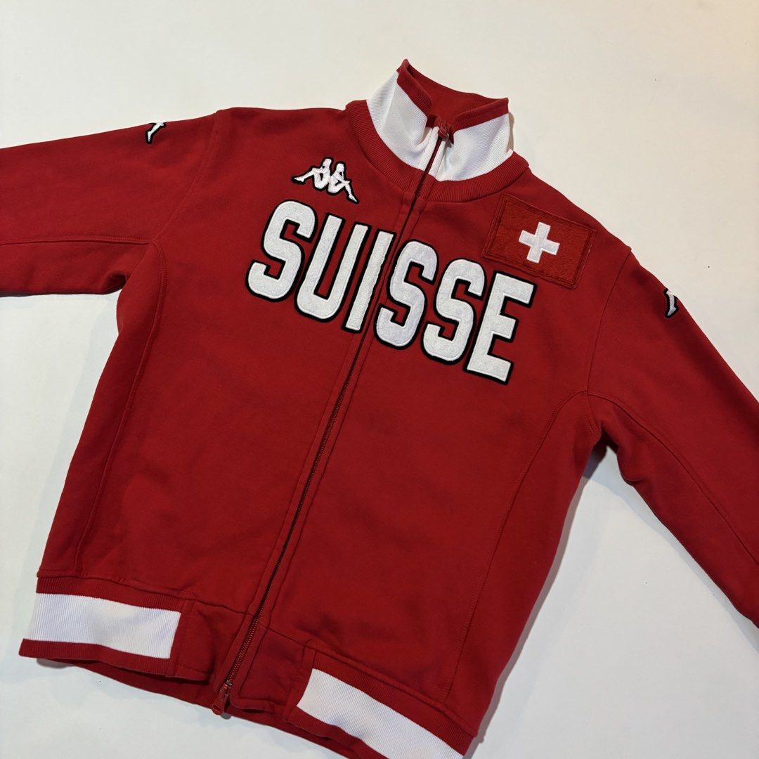 Vintage Kappa Suisse Red Track Jacket Medium (Category: Coats, Jackets and Outerwear) located in Dipolog. Submitted by dionato (Listing ID 1470777617, Image 2). Description: - Brand: Kappa - Style: Red track jacket with white ribbed collar, cuffs, and hem - Design: Large embroidered 'SUISSE' across the chest with classic Kappa logo and stitched Swiss flag patch - Hardware: Full zip front with dual pullers - Size: Medium - Material: Heavy cotton b