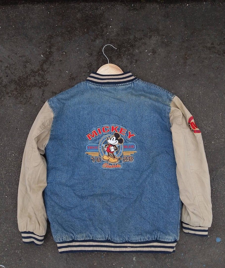 Vintage Mickey Mouse Denim Varsity Jacket (Category: Coats, Jackets and Outerwear) located in Baler. Submitted by vansonearth (Listing ID 1470752212, Image 2). Description: - Classic denim varsity jacket with Mickey Mouse graphics (front & back) - Cream-colored sleeves with ribbed striped cuffs, collar, and hem - Snap button front closure with slanted waist pockets - 1928 heritage design - Casual streetwear style, ideal for layering in colder wea