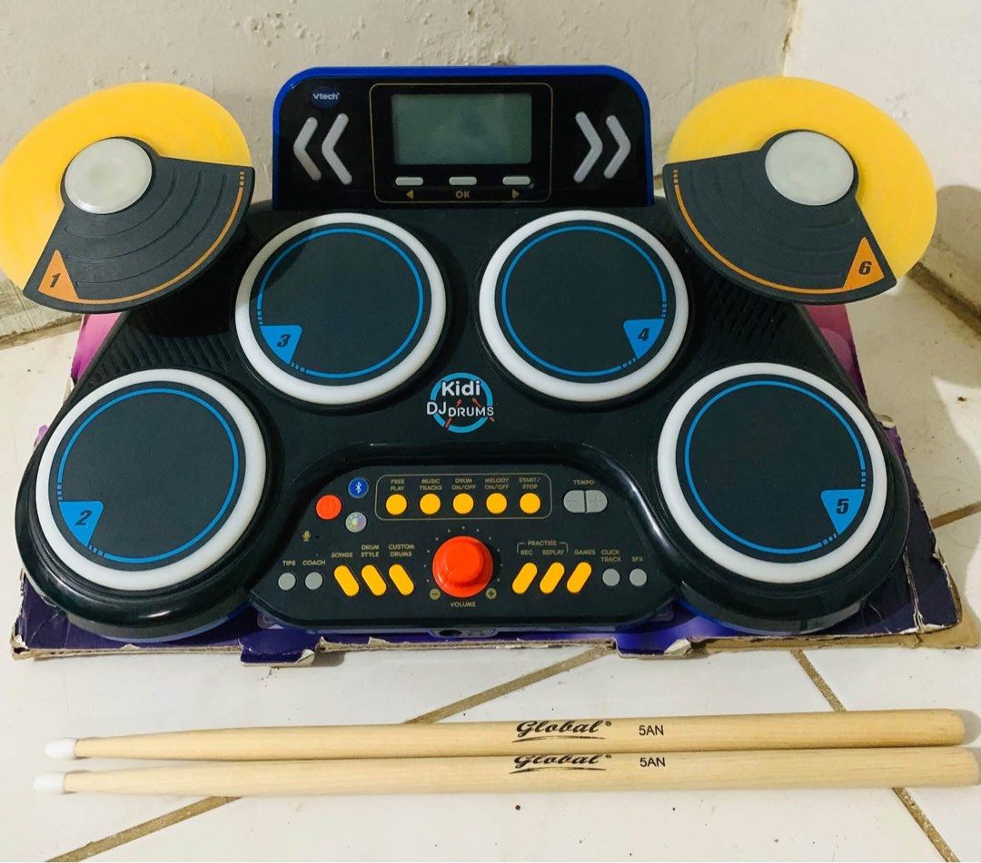 VTech Kidi DJ Drums electronic drum kit with sticks (Category: Musical Instruments) located in Cagayan de Oro. Submitted by sethmarko27 (Listing ID 1470814465, Image 1). Description: - Item: VTech Kidi DJ Drums interactive electronic toy - Features: 6 numbered pads, built-in speaker, display screen, controls, and volume knob - Inclusions: Pair of Global 5AN wooden drum sticks and original cardboard base - Condition: Great working condition, perfe