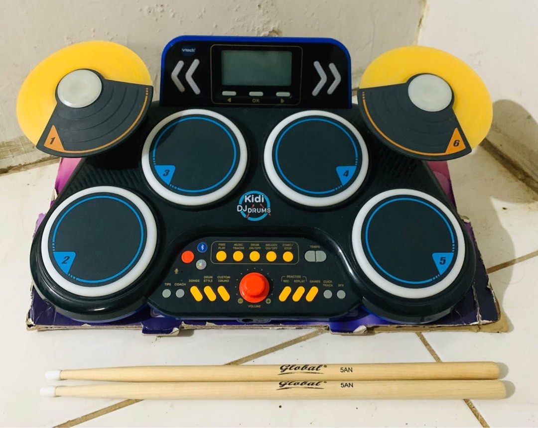 VTech Kidi DJ Drums electronic drum kit with sticks (Category: Musical Instruments) located in Cagayan de Oro. Submitted by sethmarko27 (Listing ID 1470814465, Image 2). Description: - Item: VTech Kidi DJ Drums interactive electronic toy - Features: 6 numbered pads, built-in speaker, display screen, controls, and volume knob - Inclusions: Pair of Global 5AN wooden drum sticks and original cardboard base - Condition: Great working condition, perfe