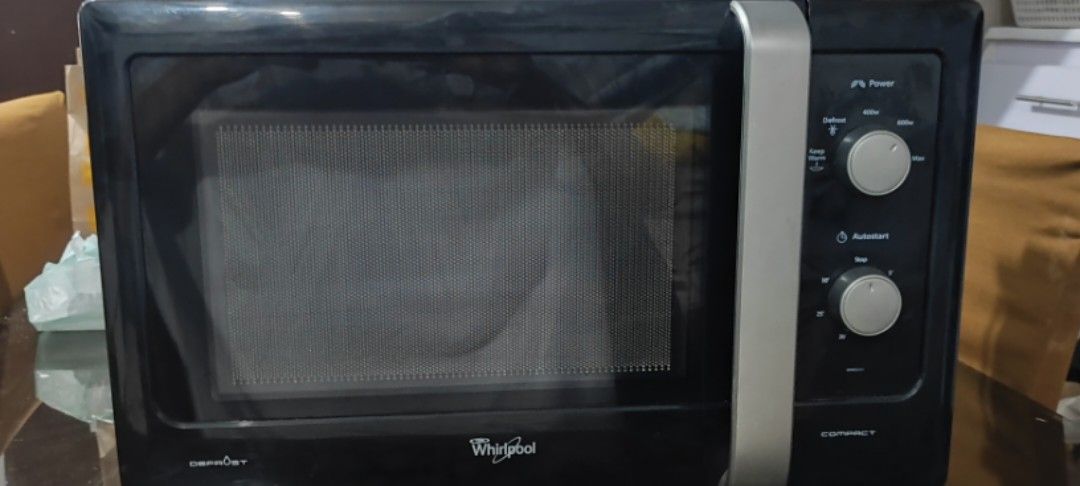 Whirlpool Compact Microwave Oven (Category: Ovens & Toasters) located in Rizal. Submitted by danicahpangilinan (Listing ID 1470822894, Image 2). Description: Black Whirlpool compact microwave oven with a vertical silver handle and dual rotary control knobs on the right panel. Interior cavity includes the rotating glass tray and turntable ring. Standard countertop footprint..