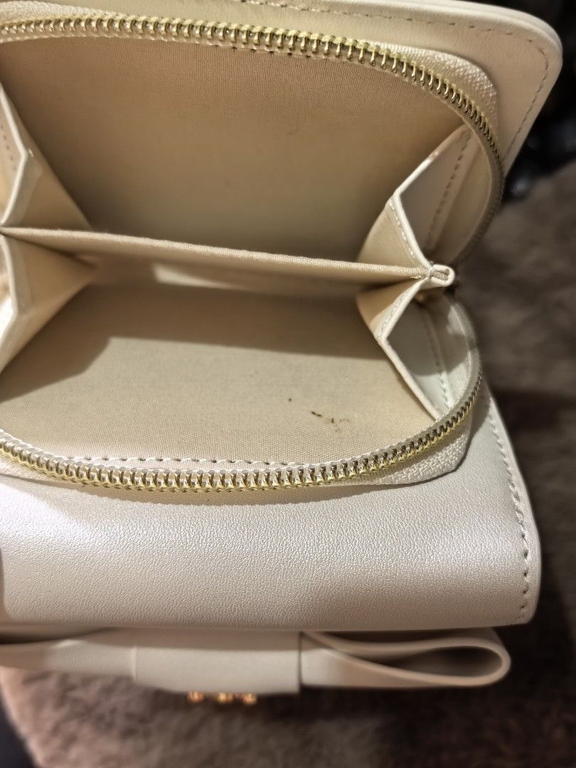 White bow wallet with gold hardware (Category: Wallets & Card holders) located in Rizal. Submitted by gkstcenit (Listing ID 1470797776, Image 3). Description: - Color: Cream white - Design: Elegant front bow with gold-tone logo monogram - Interior: Multiple card slots and a zipped coin pocket - Quality: Clean edge stitching - Size: Compact, fits easily in everyday bags.