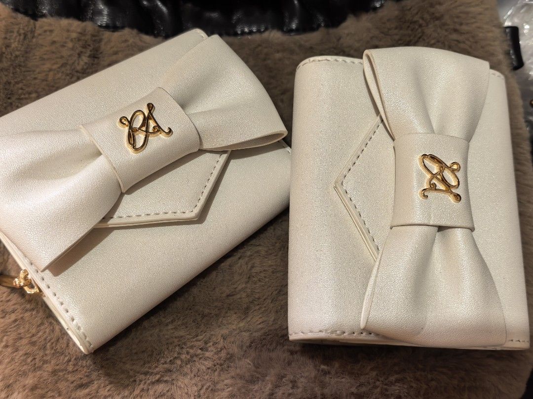 White bow wallet with gold hardware (Category: Wallets & Card holders) located in Rizal. Submitted by gkstcenit (Listing ID 1470797776, Image 2). Description: - Color: Cream white - Design: Elegant front bow with gold-tone logo monogram - Interior: Multiple card slots and a zipped coin pocket - Quality: Clean edge stitching - Size: Compact, fits easily in everyday bags.