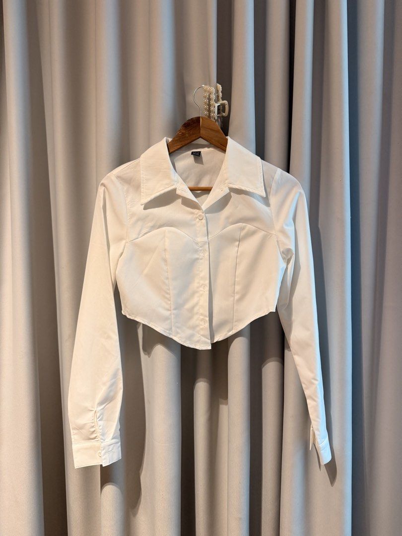 White cropped button-down shirt with pointed hem (Category: Shirts) located in Taguig. Submitted by regalbbb (Listing ID 1470754044, Image 1). Description: RFS: Decluttering Condition: Tried on once and never used - Color: White - Style: Long-sleeve button-down shirt - Fit: Fitted silhouette with a trendy cropped length - Design: Unique pointed hemline and classic collar - Versatility: Minimalist look, perfect to pair with high-waisted jeans and 