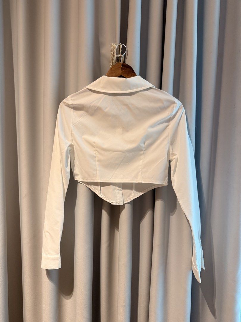 White cropped button-down shirt with pointed hem (Category: Shirts) located in Taguig. Submitted by regalbbb (Listing ID 1470754044, Image 2). Description: RFS: Decluttering Condition: Tried on once and never used - Color: White - Style: Long-sleeve button-down shirt - Fit: Fitted silhouette with a trendy cropped length - Design: Unique pointed hemline and classic collar - Versatility: Minimalist look, perfect to pair with high-waisted jeans and 