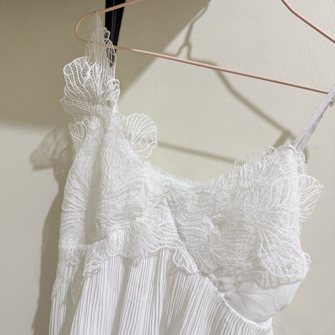 White lace pleated camisole top spaghetti strap (Category: Sleeveless) located in Cebu City. Submitted by mayanng_12 (Listing ID 1470834573, Image 2). Description: - Color: White - Style: Sleeveless camisole top with flowy, lightweight material - Details: Intricate floral lace overlay on the bodice with scalloped trim and vertical accordion pleats on the lower half - Fit: Thin adjustable shoulder straps for a customized fit - Styling: Great to pa