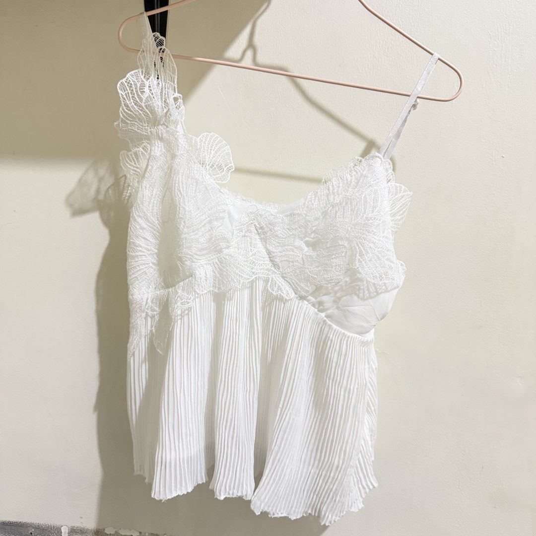 White lace pleated camisole top spaghetti strap (Category: Sleeveless) located in Cebu City. Submitted by mayanng_12 (Listing ID 1470834573, Image 1). Description: - Color: White - Style: Sleeveless camisole top with flowy, lightweight material - Details: Intricate floral lace overlay on the bodice with scalloped trim and vertical accordion pleats on the lower half - Fit: Thin adjustable shoulder straps for a customized fit - Styling: Great to pa