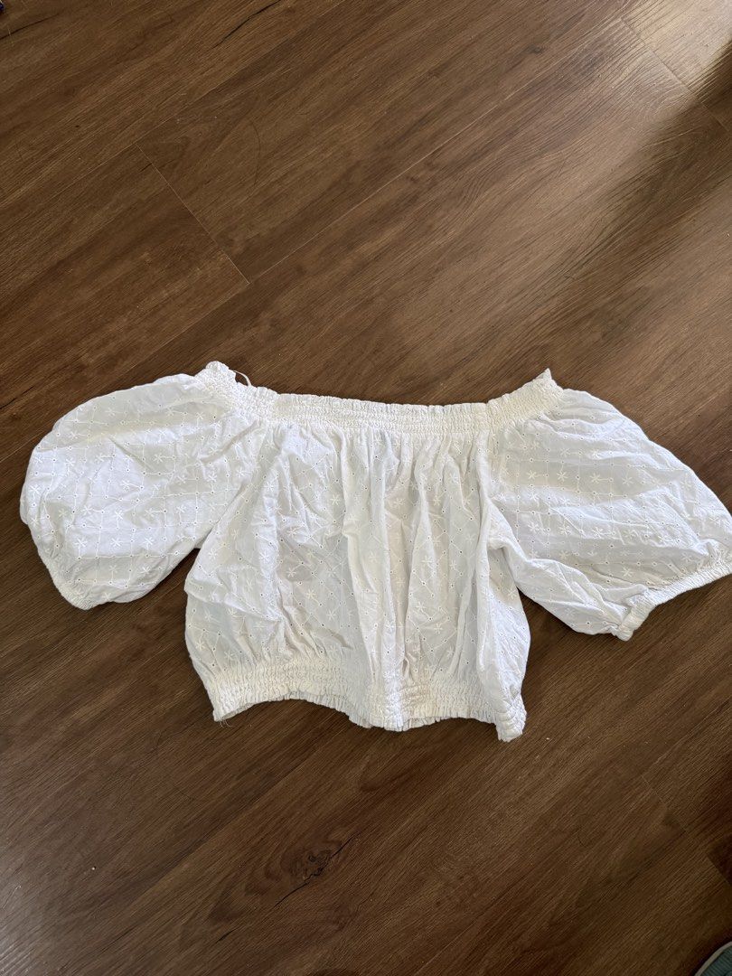 White off-shoulder crop top with eyelet embroidery (Category: Blouses) located in Manila. Submitted by yncldo (Listing ID 1470760132, Image 1). Description: - Color: White - Style: Off-shoulder crop top with short puff sleeves - Design: All-over floral eyelet embroidery pattern - Fit: Smocked elastic neckline and hem for easy stretch - Material: Lightweight fabric, ideal for warm weather.