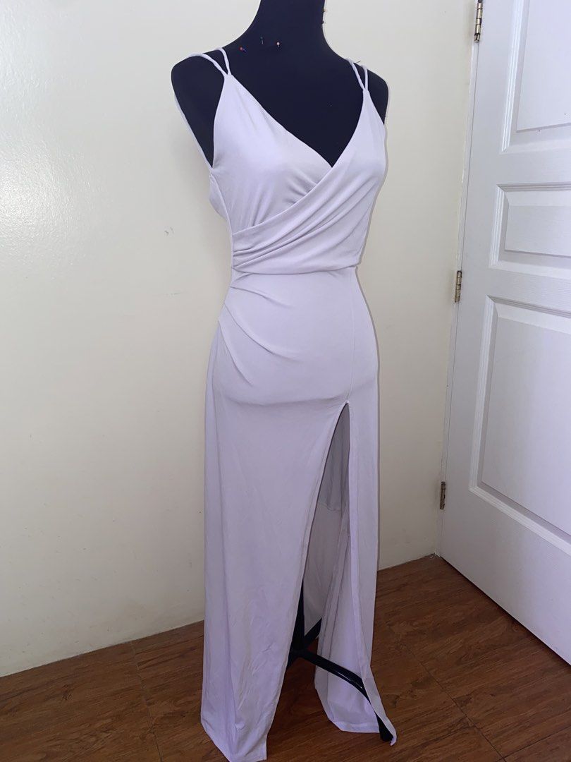 White V-neck wrap maxi dress with double straps (Category: Dresses) located in Pasay City. Submitted by violetttttttttttttt (Listing ID 1470822315, Image 1). Description: White sleeveless maxi dress. Features a crossover V-neck wrap bodice and double spaghetti straps. Back includes a low scoop cut and a hidden zipper closure down the center. Front has a high center slit starting at the thigh. Long floor-length hem with slight pooling..