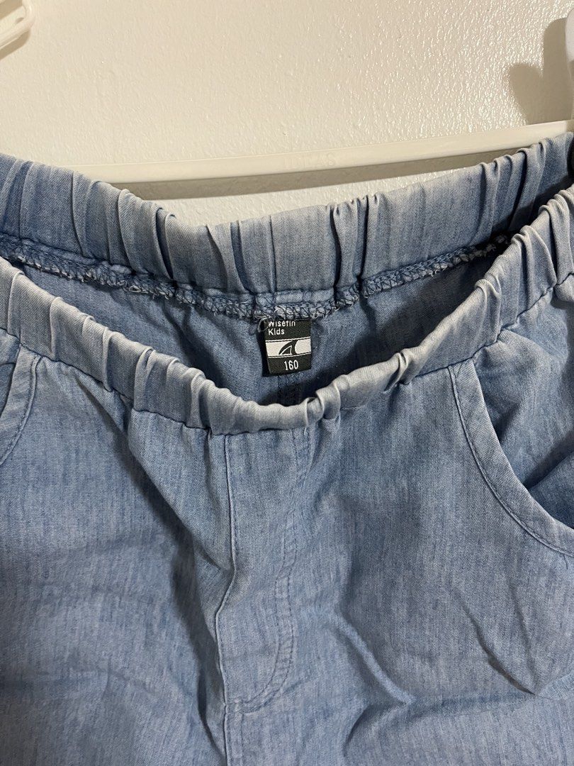 Wisetin Kids Denim Shorts (Category: Shorts) located in Cabuyao City. Submitted by rdtrmt (Listing ID 1470743780, Image 2). Description: - Brand/Style: Wisetin Kids light wash denim shorts - Size: 160 - Waistband: Comfortable elastic pull-on style - Design: Gathered cuffs, front pockets, and curved back pockets with folded ribbon details - Accents: Sparkly rhinestone graphic near the bottom hem - Material: Soft denim, ideal for daily wear and eas