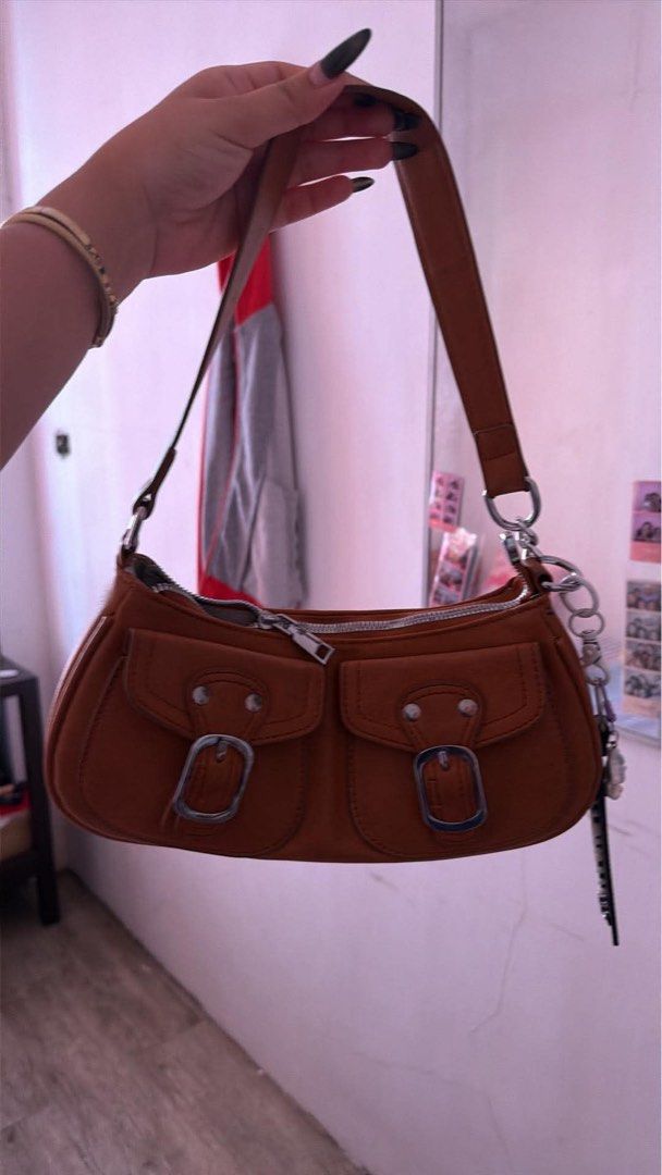 Y2k Bag (Category: Shoulder Bags) located in Badoc. Submitted by kallista.cia (Listing ID 1470749981, Image 1). Description: - Color: Classic brown - Closure: Secure top zipper - Pockets: Twin front pockets with stylish silver buckles - Straps: Single strap attached with sturdy metal rings - Extras: Trendy dangling keychain charm on the side - Size: Compact everyday size, perfect for your daily essentials.