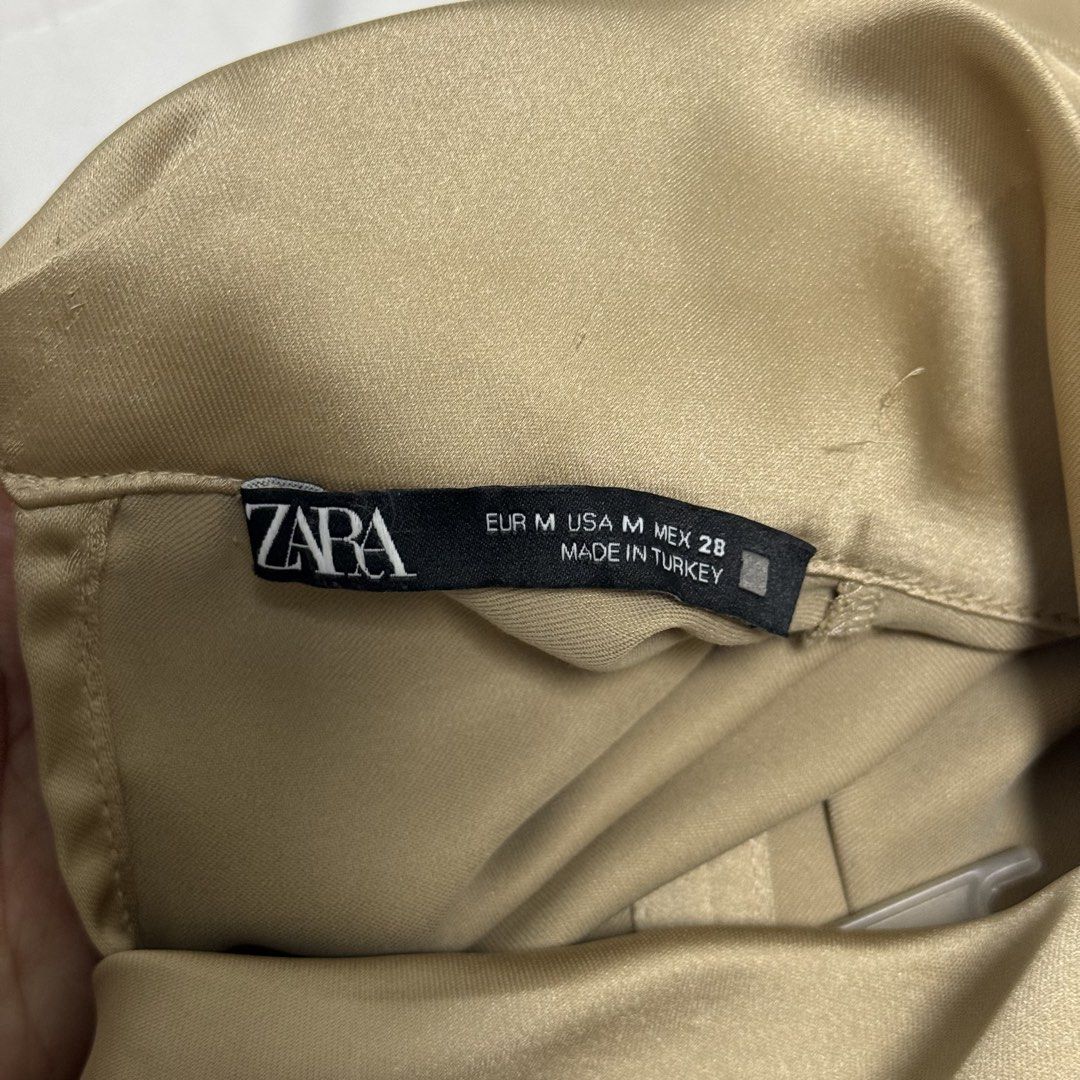 Zara Satin Sleeveless Mock Neck Top (Category: Sleeveless) located in Makati City. Submitted by angela.pm (Listing ID 1470778938, Image 2). Description: - Brand: Zara - Size: M (fits true to size) - Color/Material: Gold satin, made in Turkey - Design: Sleeveless, mock neck - Fit: Relaxed fit, drapes nicely - Condition: Great pre-loved condition - Styling: Versatile neutral piece, perfect for work or going out, easily paired with trousers or a ski