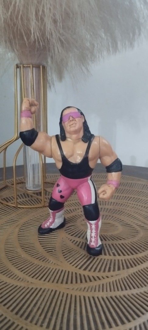 1990 Hasbro WWF Bret "The Hitman" Hart (Category: Action & Battle Toys) located in Manila. Submitted by ventajetoyz625 (Listing ID 1470954471, Image 2). Description: - Vintage WWF Hasbro Bret Hart action figure - Features his iconic pink and black singlet with heart details and pink sunglasses - Right arm sculpted in his signature pose - Condition: Shows minor paint wear on boots and hair due to age and play - Ideal for retro wrestling fans and v