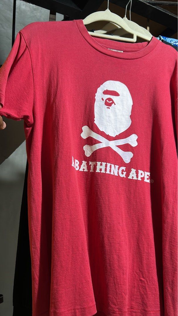 A Bathing Ape BAPE Skull & Bones Red T-Shirt (Category: Tshirts & Polo Shirts ) located in Manila. Submitted by johnlinhar98425 (Listing ID 1471077190, Image 1). Description: - Authentic A Bathing Ape (BAPE) red t-shirt - Large white Ape Head and crossbones graphic on chest - Classic A BATHING APE block lettering - Ribbed crew neck and short sleeves - 100% soft cotton - Condition: Slight fading from regular washing/wear.