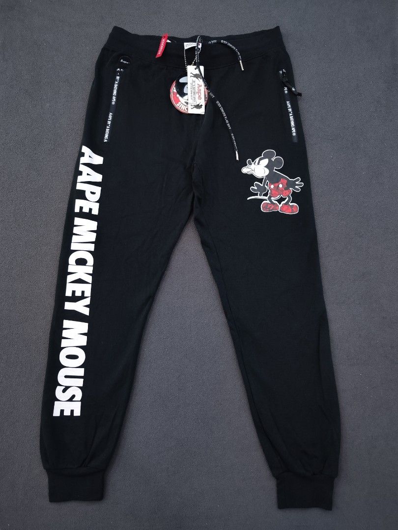 Aape X Mickey Mouse Jogger (Category: Joggers) located in Bulacan. Submitted by emilj23 (Listing ID 1470972190, Image 1). Description: Aape X Mickey Mouse Jogger Size L on tag L 36 W 30-36 Leg Hole 4 Condition 9.5/10 Color rate 9.5/10 Issue Missing Patch,Broken Zipper.