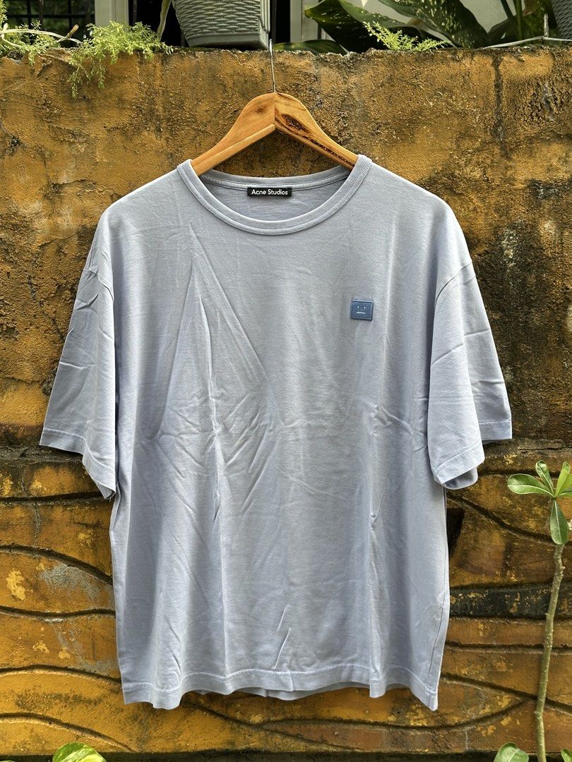 Acne Studios Face Patch Oversized T-Shirt (Category: Tshirts & Polo Shirts ) located in Urdaneta. Submitted by redeemedcollective (Listing ID 1471068712, Image 1). Description: Acne Studios crewneck T-shirt in a muted light blue-grey colorway, featuring the signature tonal Face logo patch on the chest. Details * Brand: Acne Studios * Color: Light Blue / Grey * Relaxed, oversized silhouette * Dropped shoulders * Short sleeves * Ribbed crewneck * T