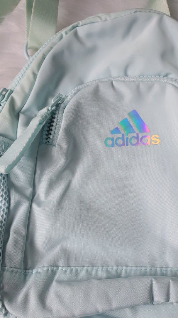 Adidas Mini Backpack Light Blue Holographic Logo (Category: Backpacks) located in Santa Rosa. Submitted by regcruz (Listing ID 1471079905, Image 1). Description: - Brand: Adidas - Color: Light blue with shiny holographic logo - Features: Main zip compartment, front zip pocket, two side mesh pockets - Straps: Adjustable pastel straps - Perfect for: Daily use, casual days, or quick errands Used 2x only.