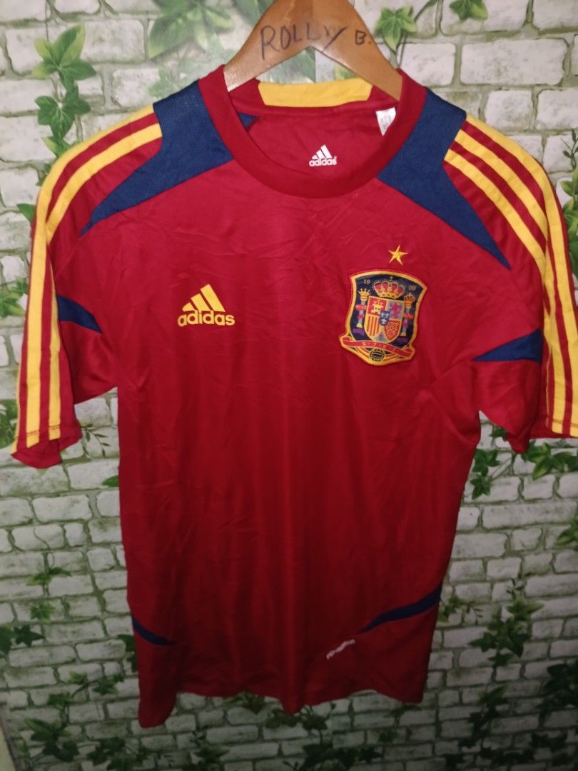 Adidas Spain 2012-13 Formotion Training Shirt Size M (Category: Activewear) located in Carcar. Submitted by rolandobac92675 (Listing ID 1470969710, Image 2). Description: - Authentic Spain national team training shirt (2012-2013 season) - Color: Red with blue and yellow accents - Features Adidas Formotion technology - Printed crest with 1 championship star on the chest - Size: Medium - Made in China (Product Code: X16736) - Perfect condition for 