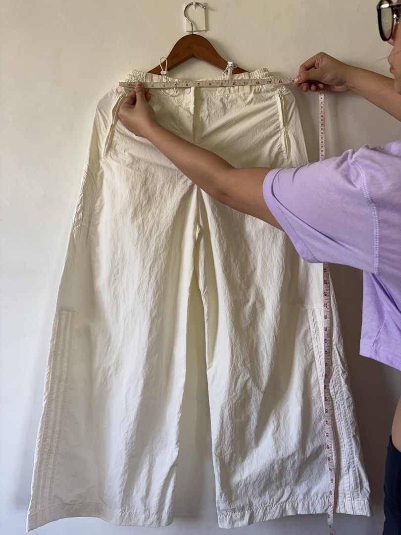 Adidas White Nylon Track Pants Size M (Category: Other Bottoms) located in Muntinlupa City. Submitted by shopkidsandmom.ph (Listing ID 1471035904, Image 2). Description: - Brand: Adidas - Color: White - Material: 100% recycled polyamide (lightweight parachute style) - Fit: Relaxed wide-leg - Waistband: Elastic with adjustable pull cords - Details: Iconic three stripes on sides, small trefoil logo near pocket - Origin: Made in China - Condition: E