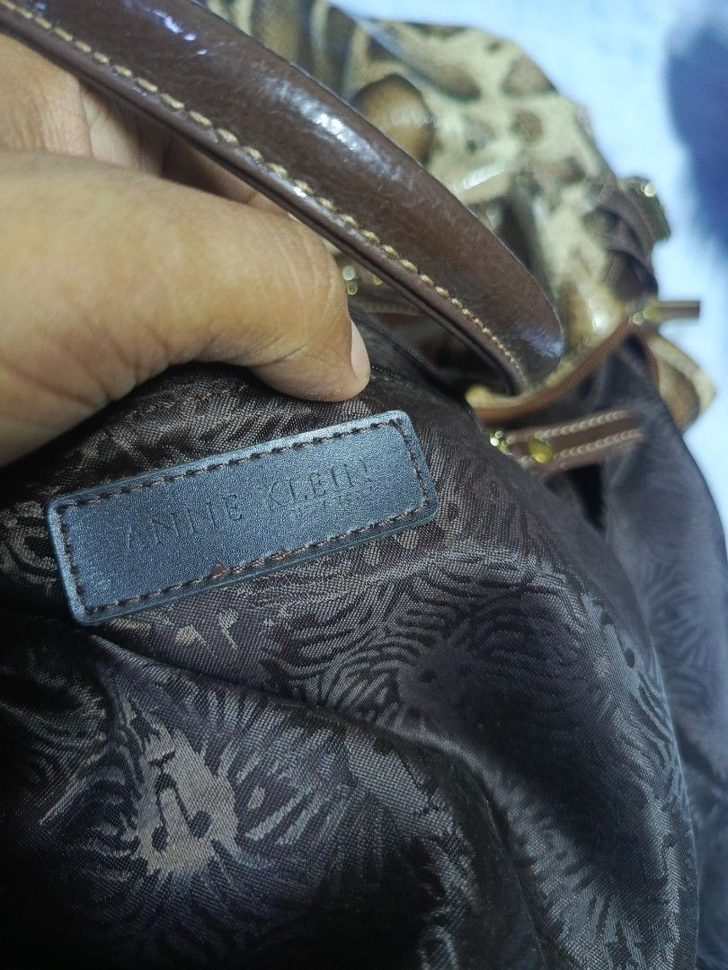 Anne Klein Animal Print Handbag (Category: Luxury Bags & Wallets) located in City of Isabela. Submitted by warmbird.d06e6f (Listing ID 1470961747, Image 3). Description: - Brand: Anne Klein - Design: Brown and cream animal print with shiny patent finish handles and trim - Hardware: Elegant gold-tone front plaque - Pockets: Convenient exterior zipper pocket on the back - Interior: Dark fabric lining with signature lion motif pattern and brand patc