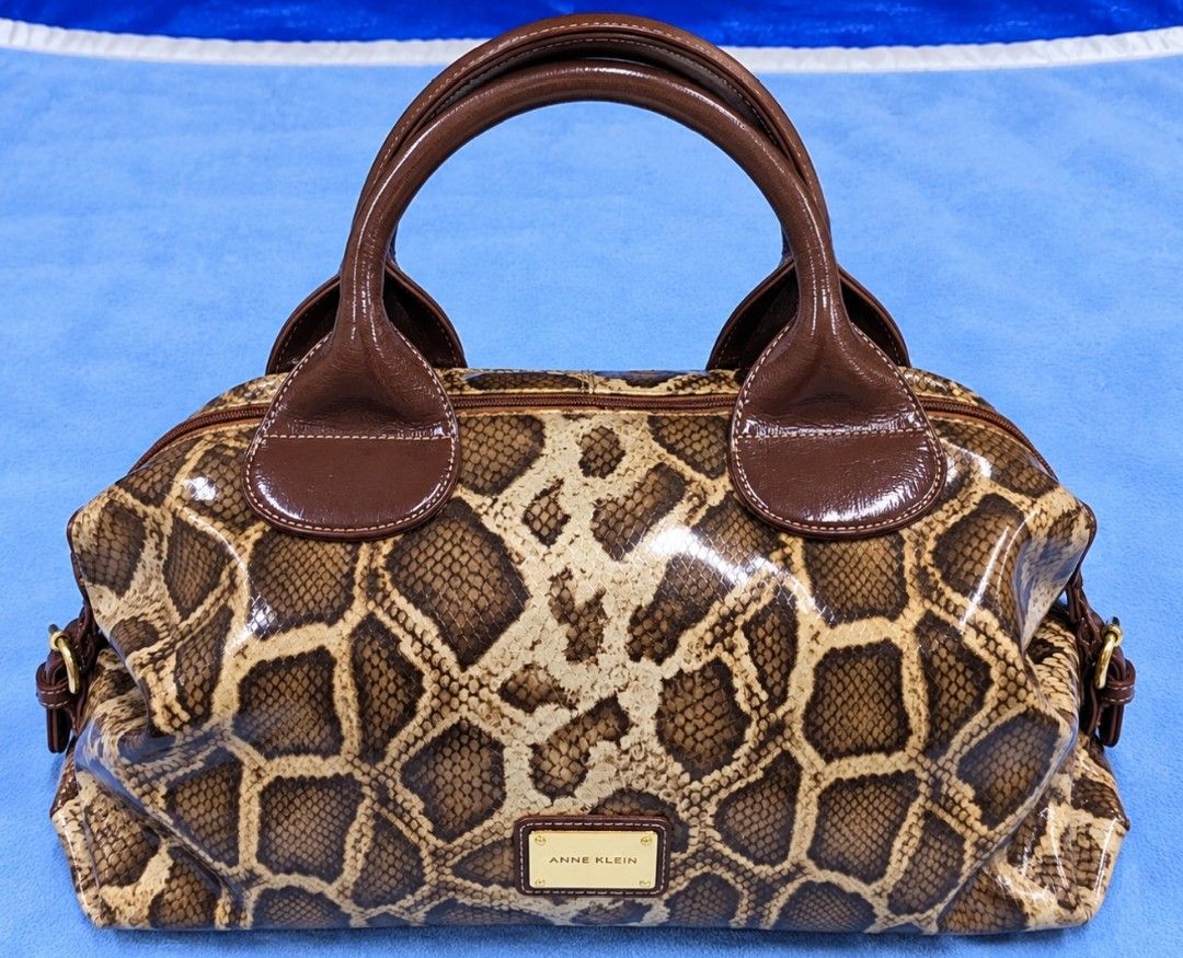 Anne Klein Animal Print Handbag (Category: Luxury Bags & Wallets) located in City of Isabela. Submitted by warmbird.d06e6f (Listing ID 1470961747, Image 1). Description: - Brand: Anne Klein - Design: Brown and cream animal print with shiny patent finish handles and trim - Hardware: Elegant gold-tone front plaque - Pockets: Convenient exterior zipper pocket on the back - Interior: Dark fabric lining with signature lion motif pattern and brand patc