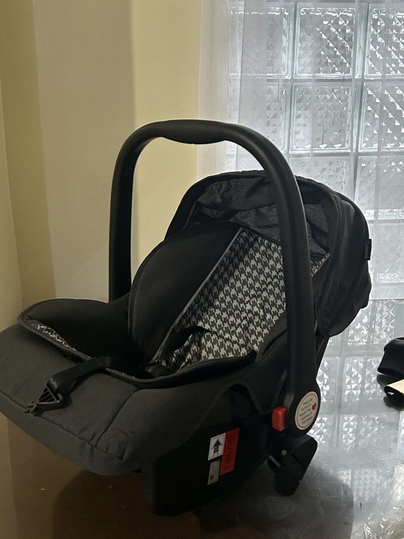 Apruva Infant Car Seat Grey Houndstooth (Category: Car Seats) located in Manila. Submitted by jovy_mae (Listing ID 1470996980, Image 3). Description: - Brand: Apruva Baby Car Seat - Color/Design: Chic grey with a trendy houndstooth pattern cushion - Safety: Built-in harness straps, central buckle, safety certification labels, and side airbag warning sticker - Convenience: Adjustable carry handle with red release buttons on both sides and an attac