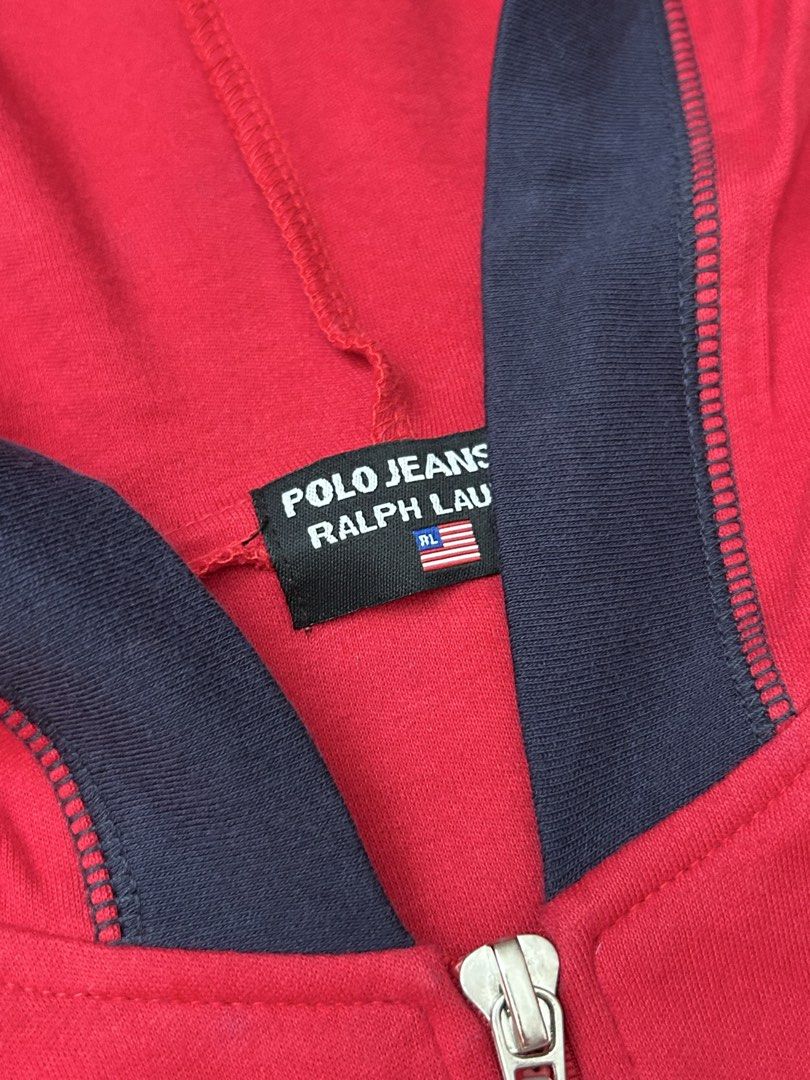Auth Polo Jeans Ralph Lauren Zip Up Jacket (Category: Coats, Jackets and Outerwear) located in Paranaque City. Submitted by madenise_declutter (Listing ID 1470976956, Image 3). Description: Vibrant red zip-up hoodie from Polo Jeans Co. Ralph Lauren. Navy blue contrast panels on the hood and sides. American flag graphic printed on the chest with Polo Jeans Co. and Ralph Lauren branding. Custom branded zipper pull tab with miniature flag detail. In