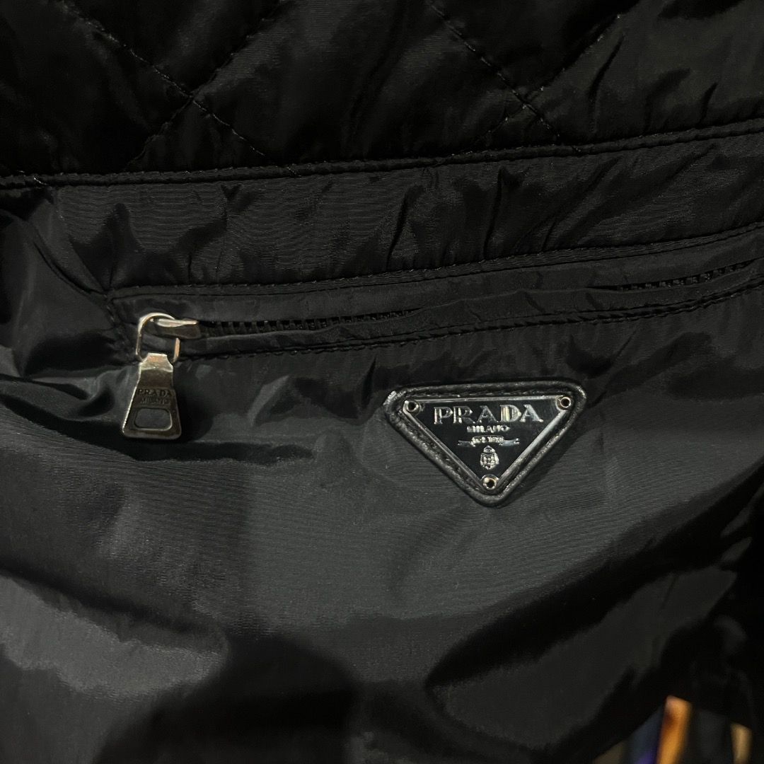 Authentic Prada Black Emblem Quilted Nylon Zip Up Jacket (Category: Coats, Jackets and Outerwear) located in Caloocan City. Submitted by achilles_grails (Listing ID 1471028486, Image 3). Description: - Brand: Prada - Item: Black quilted nylon jacket - Size: 40 - Details: Full zip front, stand collar, ribbed cuffs and hem - Feature: Lower front zipper pocket with classic Prada triangular metal logo plaque - Authenticity: Includes interior brand la