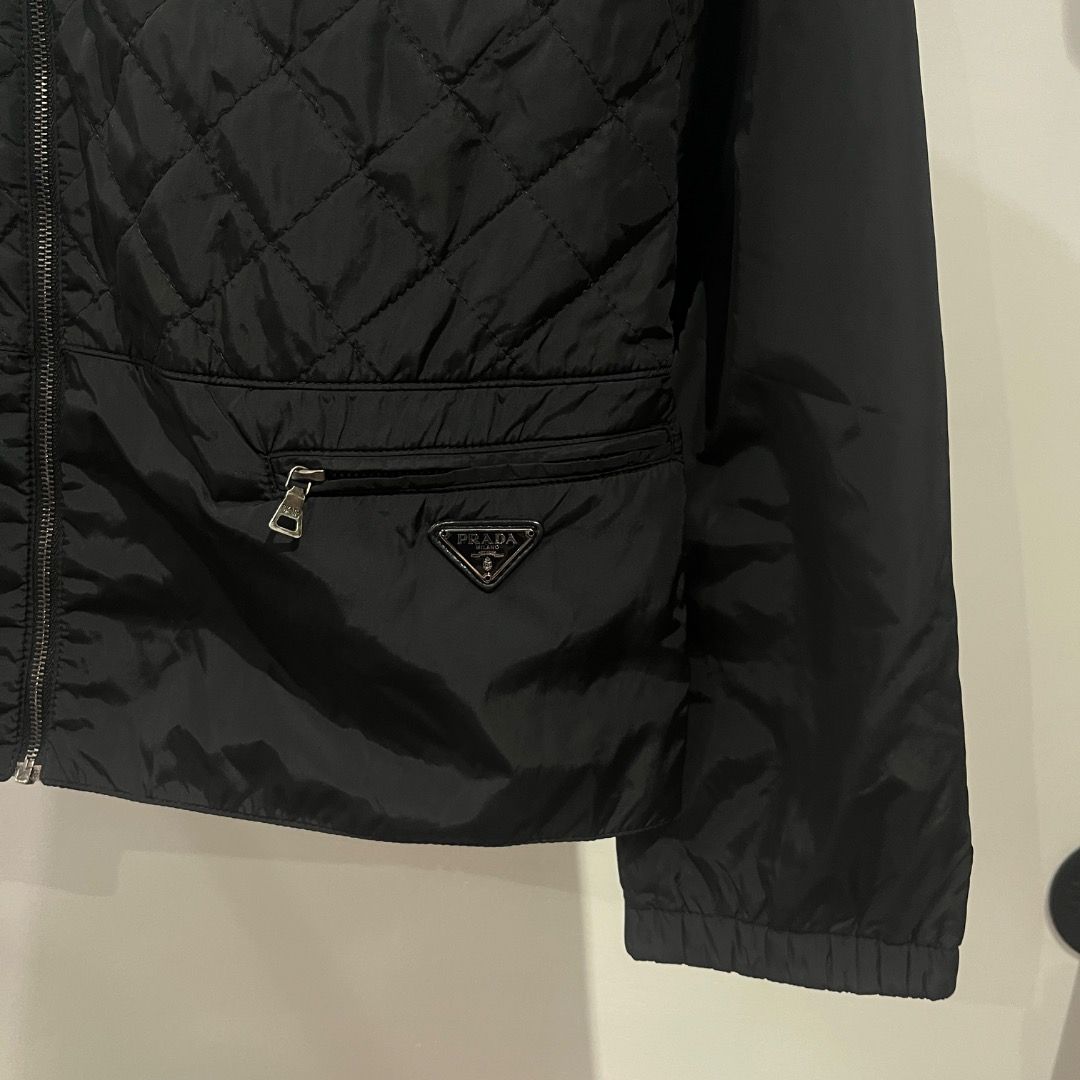 Authentic Prada Black Emblem Quilted Nylon Zip Up Jacket (Category: Coats, Jackets and Outerwear) located in Caloocan City. Submitted by achilles_grails (Listing ID 1471028486, Image 2). Description: - Brand: Prada - Item: Black quilted nylon jacket - Size: 40 - Details: Full zip front, stand collar, ribbed cuffs and hem - Feature: Lower front zipper pocket with classic Prada triangular metal logo plaque - Authenticity: Includes interior brand la