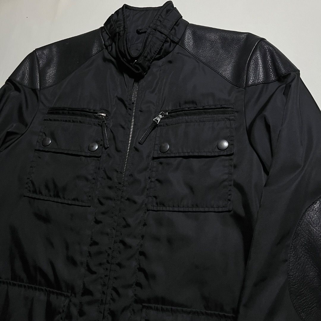 Authentic Prada Black Nylon Utility Jacket with Leather Accents (Category: Luxury Apparel) located in Caloocan City. Submitted by achilles_grails (Listing ID 1471039912, Image 2). Description: - Authentic Prada nylon utility jacket in classic black - Full front zip closure with high funnel neck and snap buttons - Multiple practical cargo pockets and zippered compartments - Stylish textured leather panels on shoulders and elbow patches - Premium b