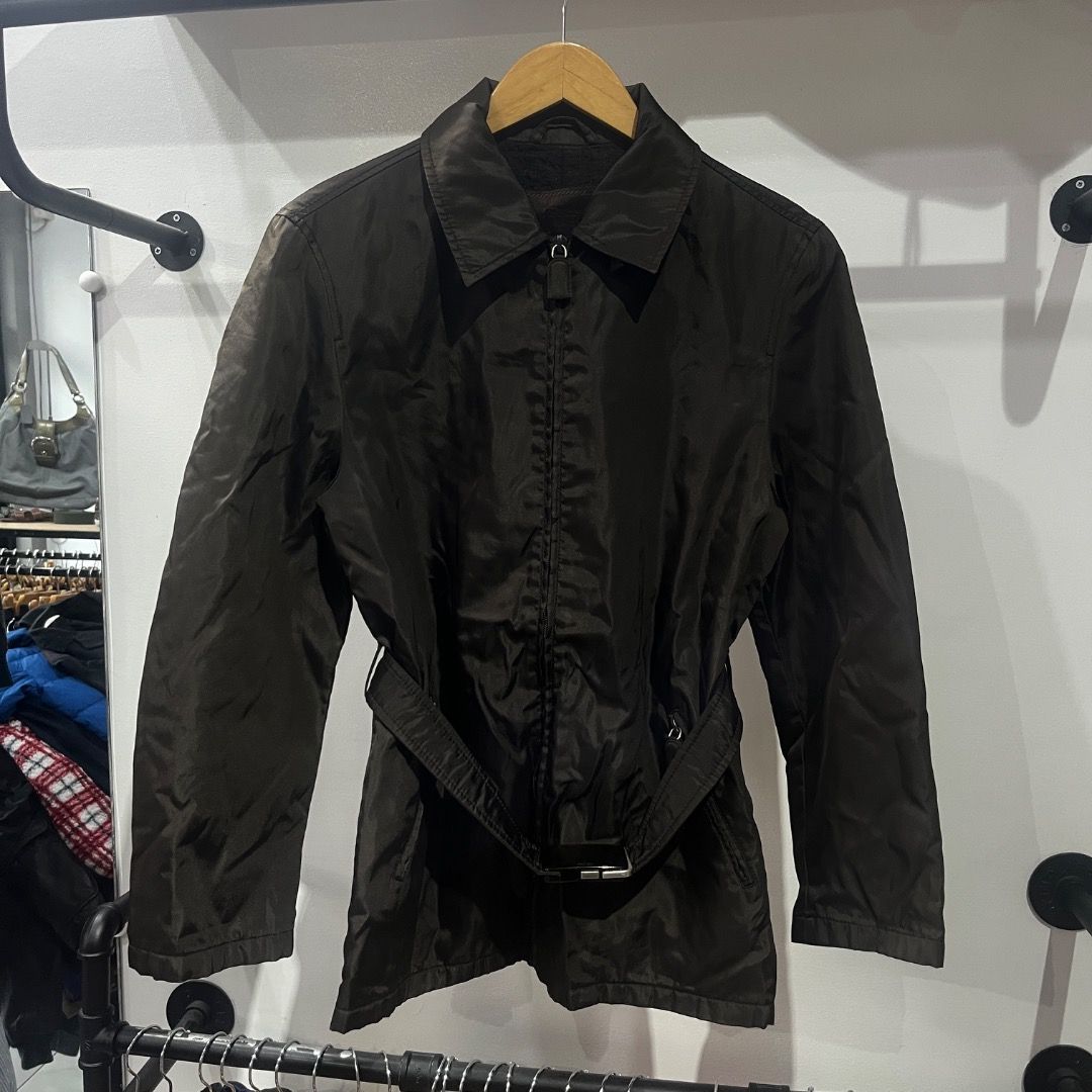 Authentic Prada Nylon Belted Trench Coat (Category: Coats, Jackets and Outerwear) located in Caloocan City. Submitted by achilles_grails (Listing ID 1471028182, Image 1). Description: - Brand: Prada - Color: Classic Black - Material: Lightweight nylon - Features: Full front zip closure, pointed collar, and long sleeves - Included: Matching fabric belt with silver-tone Prada-engraved buckle - Style: Timeless layering piece.