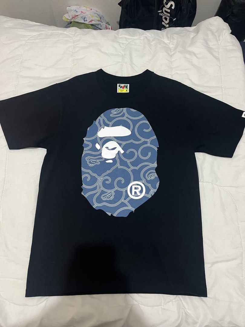 BAPE Blue Wave Ape Head (Category: Tshirts & Polo Shirts ) located in Manila. Submitted by westbridge007 (Listing ID 1471071548, Image 1). Description: BAPE Blue Wave Ape Head Graphic T-Shirt – Black Price: ₱3,000 Size: Medium (M, tag shown) Condition: Pre-owned / Very good condition Black BAPE graphic tee featuring a large blue pattern ape head design with white detailing. * Unique blue graphic * Black base color * Short sleeves * Front and back