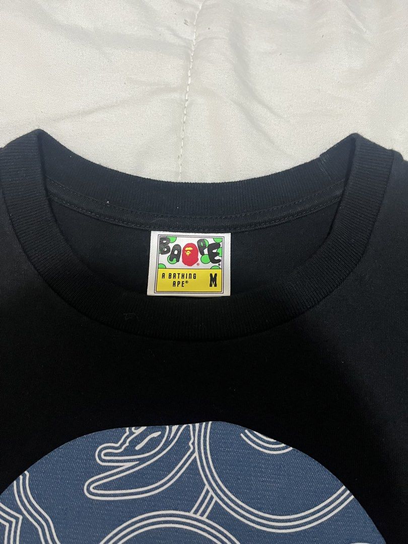 BAPE Blue Wave Ape Head (Category: Tshirts & Polo Shirts ) located in Manila. Submitted by westbridge007 (Listing ID 1471071548, Image 3). Description: BAPE Blue Wave Ape Head Graphic T-Shirt – Black Price: ₱3,000 Size: Medium (M, tag shown) Condition: Pre-owned / Very good condition Black BAPE graphic tee featuring a large blue pattern ape head design with white detailing. * Unique blue graphic * Black base color * Short sleeves * Front and back
