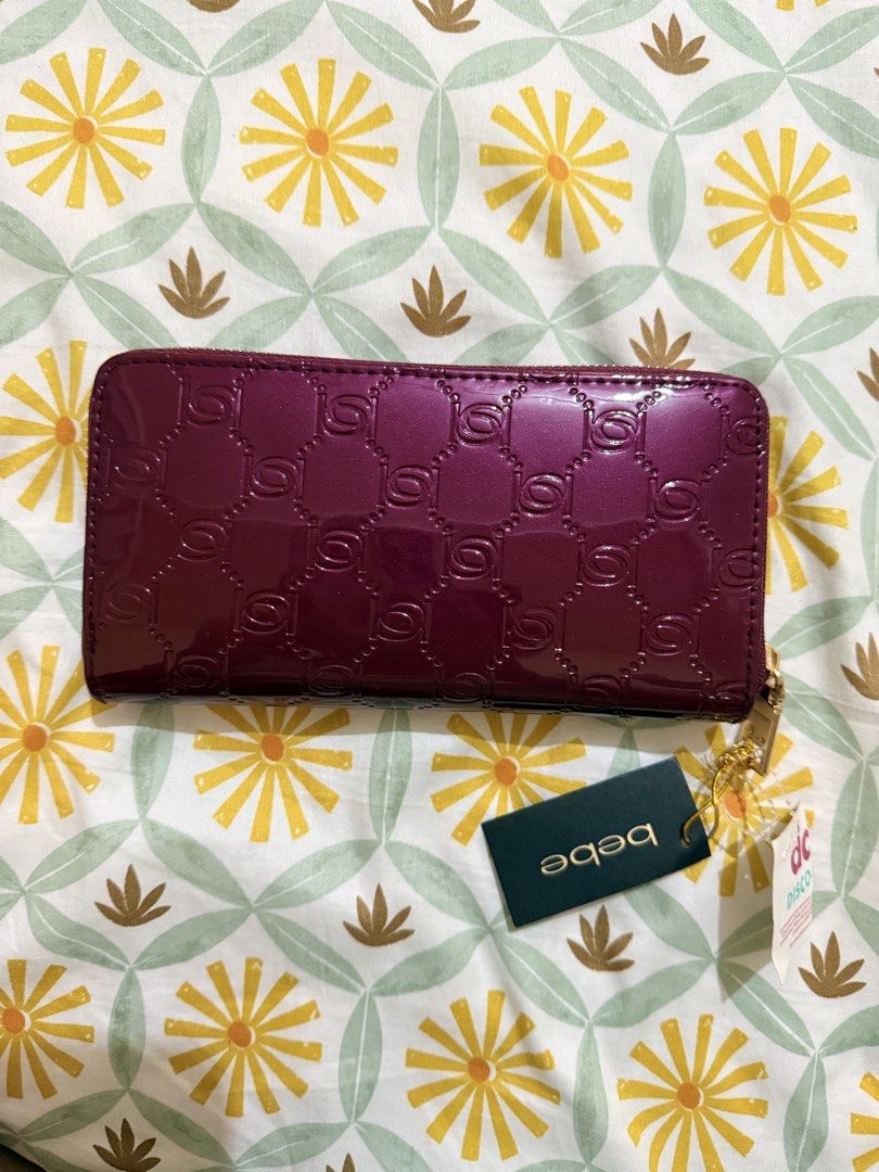 bebe Purple Patent Logo Zip Around Wallet (Category: Wallets & Card holders) located in Marikina City. Submitted by delapaz.erica (Listing ID 1470982313, Image 2). Description: - Brand: bebe - Color/Finish: Maroon patent with all-over debossed monogram - Hardware: Gold-tone with front metal logo plaque - Closure: Zip-around - Interior: Multiple card slots and zipped coin pocket - Condition: Brand new with original tags (MSRP $49.00) Location: Mar