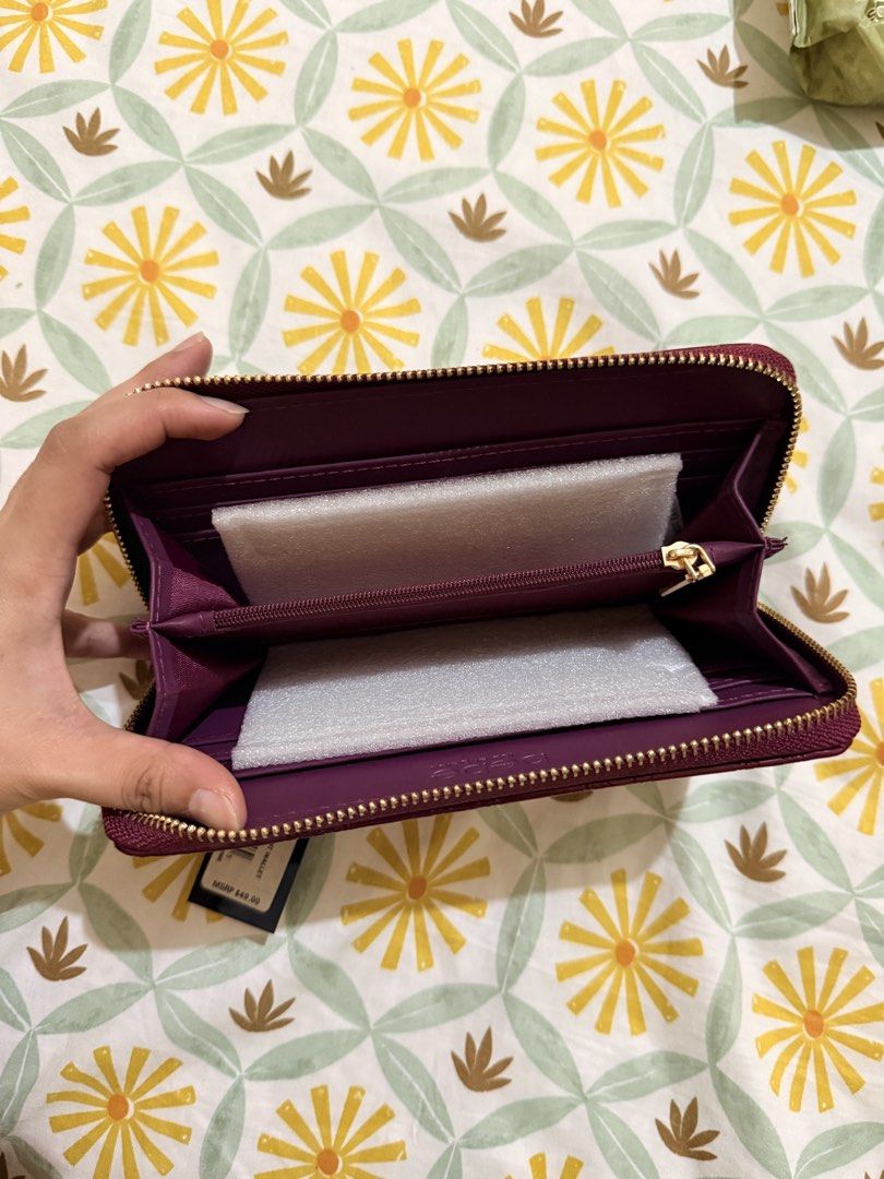bebe Purple Patent Logo Zip Around Wallet (Category: Wallets & Card holders) located in Marikina City. Submitted by delapaz.erica (Listing ID 1470982313, Image 3). Description: - Brand: bebe - Color/Finish: Maroon patent with all-over debossed monogram - Hardware: Gold-tone with front metal logo plaque - Closure: Zip-around - Interior: Multiple card slots and zipped coin pocket - Condition: Brand new with original tags (MSRP $49.00) Location: Mar