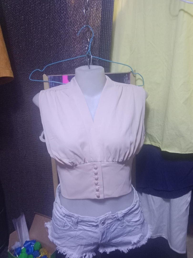 Beige V-Neck Crop Top with Front Buttons (Category: Blouses) located in Quezon City. Submitted by honeyonline.ph (Listing ID 1471040459, Image 3). Description: - Style: Sleeveless crop top with deep V-neckline - Details: Gathered bodice and fitted waist panel with center-front buttons - Color: Versatile neutral beige - Pairing: Matches easily with denim shorts, skirts, or high-waisted pants - Condition: Brand new with clean interior tag.