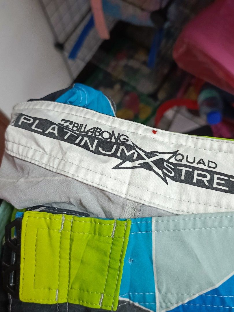 Billabong Platinum X Quad Stretch Board Shorts (Category: Swim Trunks & Board Shorts) located in Manila. Submitted by christian_22 (Listing ID 1471083469, Image 3). Description: Billabong board shorts with geometric color block pattern in black, lime green, bright blue, and light grey. Platinum X quad stretch fabric. Side pocket with bungee cord loop and Billabong logo tag. Iconic wave logo patch near the hem. Inner waistband has branding print. 