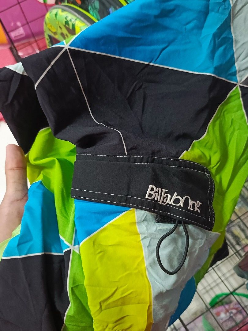 Billabong Platinum X Quad Stretch Board Shorts (Category: Swim Trunks & Board Shorts) located in Manila. Submitted by christian_22 (Listing ID 1471083469, Image 2). Description: Billabong board shorts with geometric color block pattern in black, lime green, bright blue, and light grey. Platinum X quad stretch fabric. Side pocket with bungee cord loop and Billabong logo tag. Iconic wave logo patch near the hem. Inner waistband has branding print. 