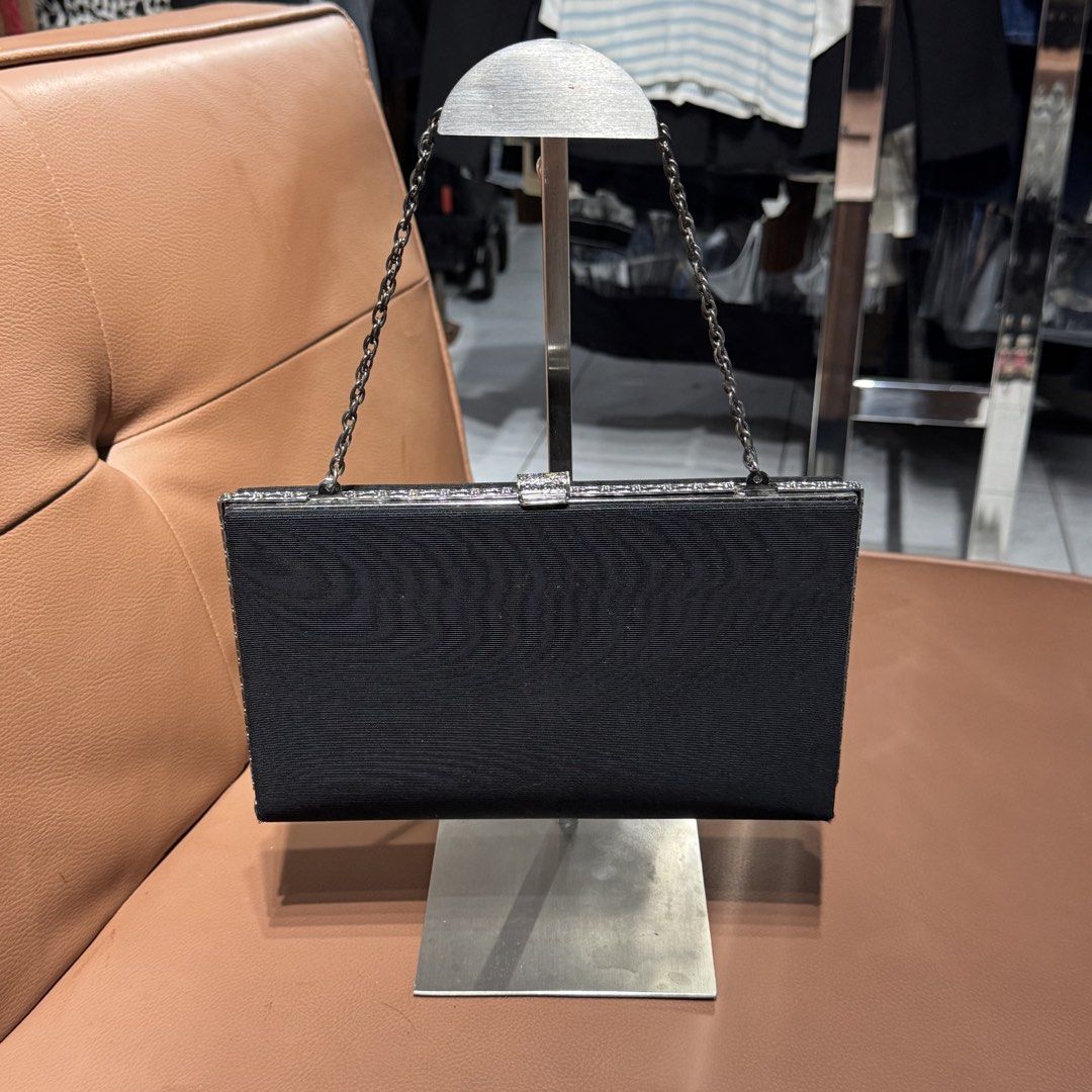 Black Evening Clutch Bag with Chain Strap and Silver Trim (Category: Clutches) located in Rizal. Submitted by houseofbell (Listing ID 1471100549, Image 2). Description: Black fabric evening clutch. Silver metallic frame with crystal-like embellishments along the edges and clasp closure. Thin chain strap attached. Interior features accordion sides, slip pocket, and lined fabric. Clean condition overall. Good size for cards, keys, and phone during 