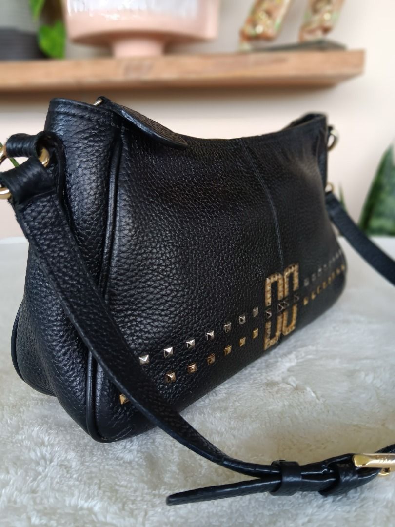 DAKS Black Leather Shoulder Bag (Category: Luxury Bags & Wallets) located in Pateros City. Submitted by sphinxvillanueva (Listing ID 1471050336, Image 2). Description: - Color & Material: Classic black pebbled leather - Hardware: Premium gold-tone with geometric double 'D' center emblem - Details: Chic studded detailing along the lower front panel - Strap: Adjustable matching black strap with secure lobster clasp attachments - Closure: Zip-top cl