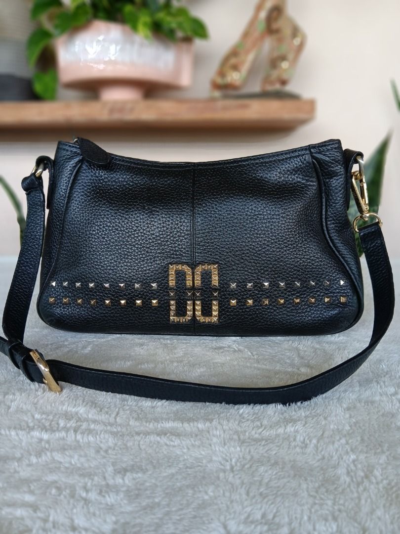 DAKS Black Leather Shoulder Bag (Category: Luxury Bags & Wallets) located in Pateros City. Submitted by sphinxvillanueva (Listing ID 1471050336, Image 1). Description: - Color & Material: Classic black pebbled leather - Hardware: Premium gold-tone with geometric double 'D' center emblem - Details: Chic studded detailing along the lower front panel - Strap: Adjustable matching black strap with secure lobster clasp attachments - Closure: Zip-top cl