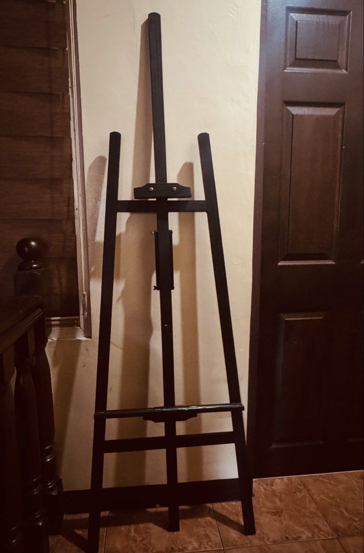 Black Wooden Artist Display Easel (Category: Art & Prints) located in Las Pinas. Submitted by emdjss (Listing ID 1471001526, Image 1). Description: - Sturdy A-frame wooden easel in a sleek matte black finish - Adjustable center mast fits different canvas and sign sizes - Solid construction ensures floor stability - Clean condition with no wood damage - Ideal for painting, art displays, or event signs.
