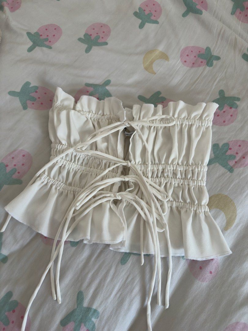 BSCO White Ruched Crop Top with Ties Size Small (Category: Sleeveless) located in Manila. Submitted by preloved-bycath (Listing ID 1471078868, Image 1). Description: - Brand: BSCO - Size: PH Small - Color: White - Material: Stretchy fabric, made in the Philippines - Design: Front ribbon ties with multiple closures, ruched texture, and ruffle hem trim - Condition: Brand new / Excellent.