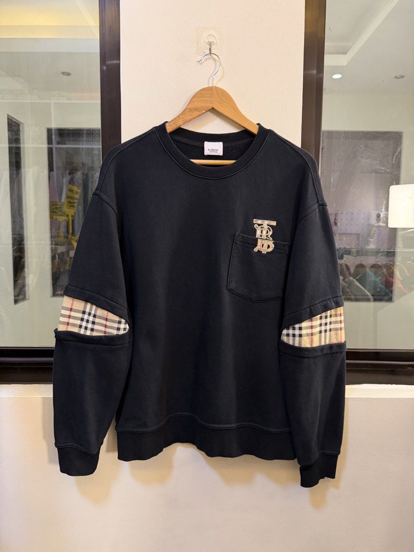 Burberry Crewneck Sweatshirt (Category: Coats, Jackets and Outerwear) located in Paranaque City. Submitted by preluxeshop_ph (Listing ID 1471015574, Image 2). Description: Brand: Burberry London, England •Style: Crewneck Sweatshirt / Pullover •Color: Black •Design Features: Embroidered TB monogram logo on the left chest pocket, distinctive vintage check plaid inserts along both sleeves, crew neckline, and ribbed collar, cuffs, and hem •Material C